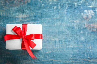 Elegant gift box with bow on wooden background, top view