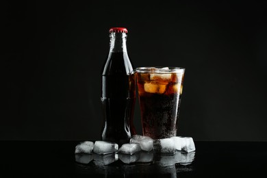 Bottle and glass of refreshing soda water on black background