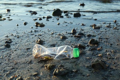 Used plastic bottle near water at beach. Environment pollution