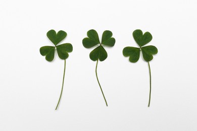 Photo of Green clover leaves on white background, flat lay