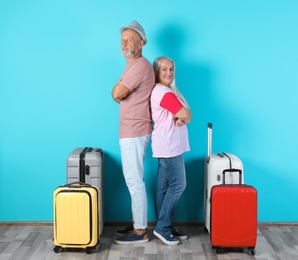 Photo of Senior couple with suitcases near color wall. Vacation travel