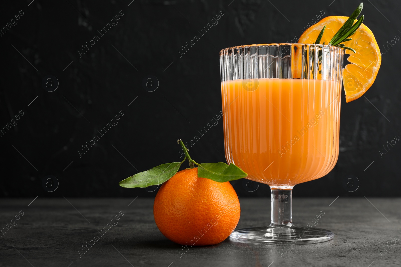 Photo of Delicious tangerine liqueur in glass and fresh fruit on grey table, space for text