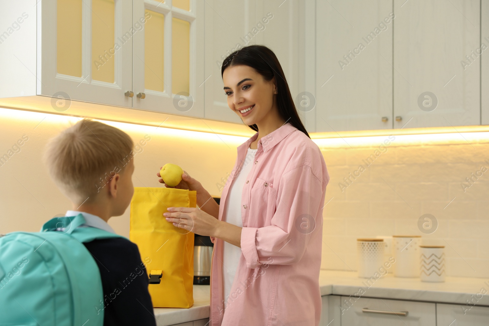 Photo of Young mother helping her little child get ready for school in kitchen