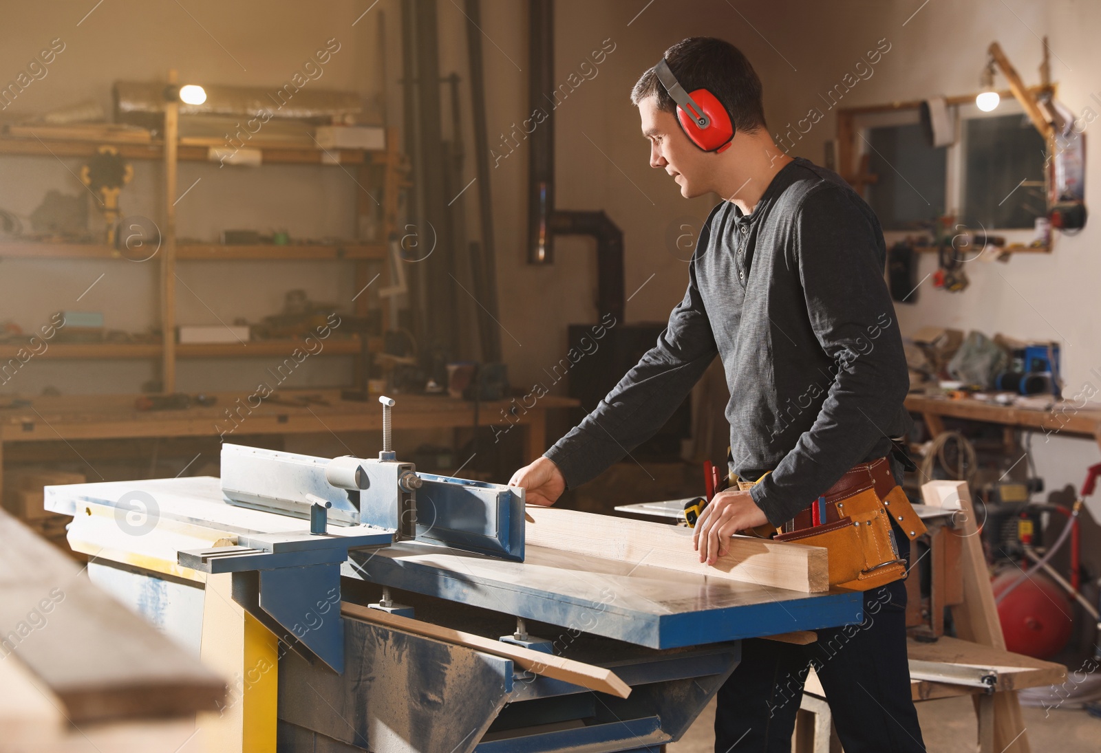 Photo of Professional carpenter working with surface planer in workshop