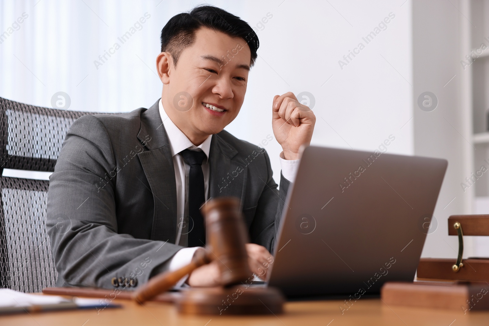 Photo of Happy notary working with laptop at wooden table in office