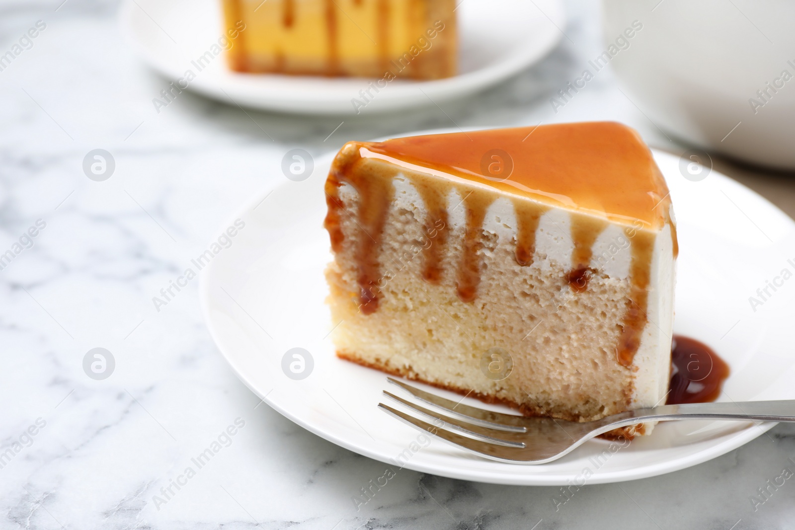 Photo of Slice of delicious cake with caramel sauce on white marble table