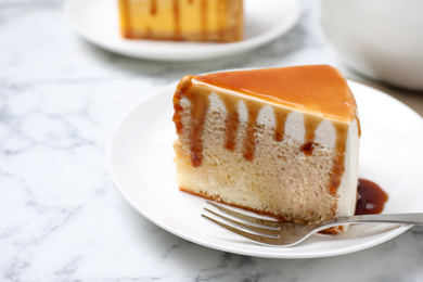 Photo of Slice of delicious cake with caramel sauce on white marble table