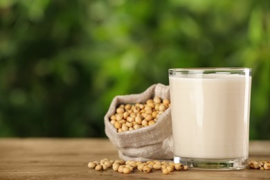 Photo of Glass with fresh soy milk and grains on white wooden table against blurred background. Space for text