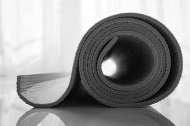 Rolled karemat or fitness mat on floor indoors, closeup. Space for text