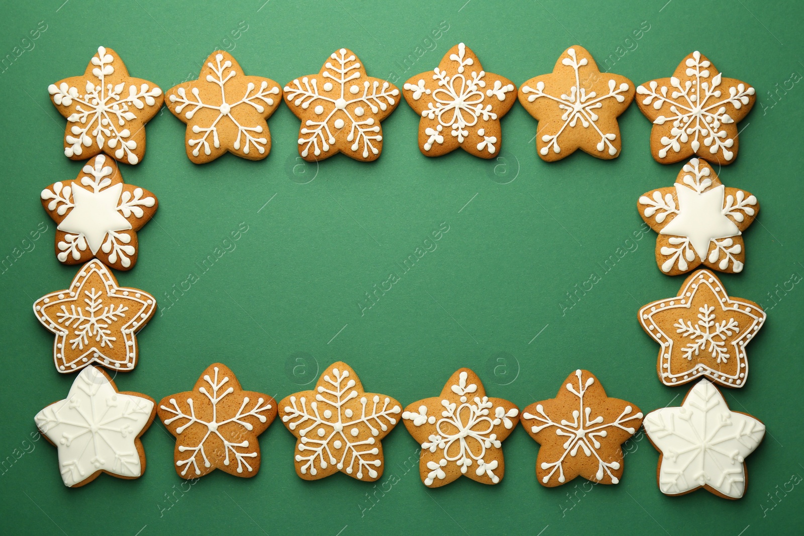 Photo of Frame made of tasty Christmas cookies with icing on green background, flat lay. Space for text