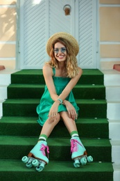 Happy girl with retro roller skates sitting on stairs