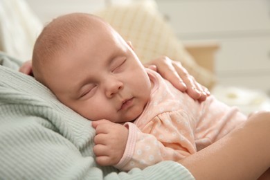 Photo of Mother holding her sleeping baby indoors, closeup