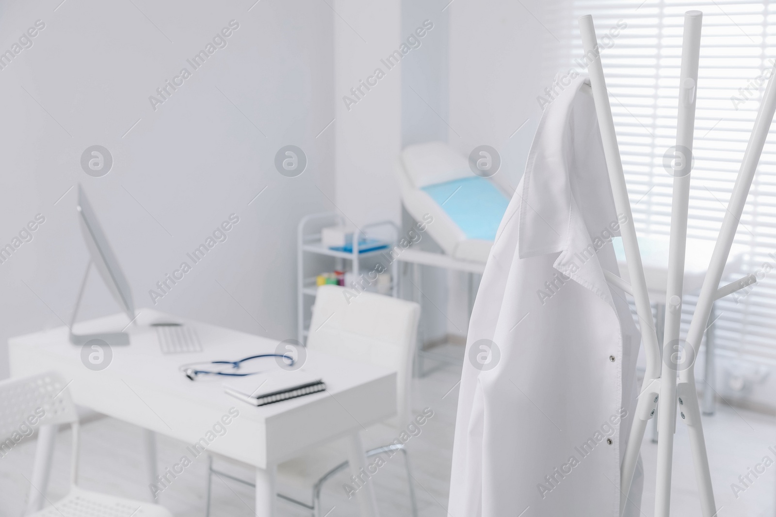 Photo of White doctor's gown hanging on rack in clinic. Space for text