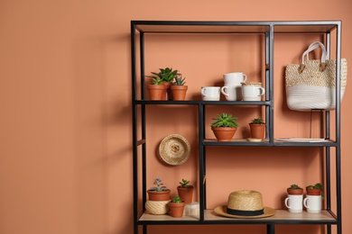 Photo of Stylish shelving unit with decorative elements near color wall. Space for text