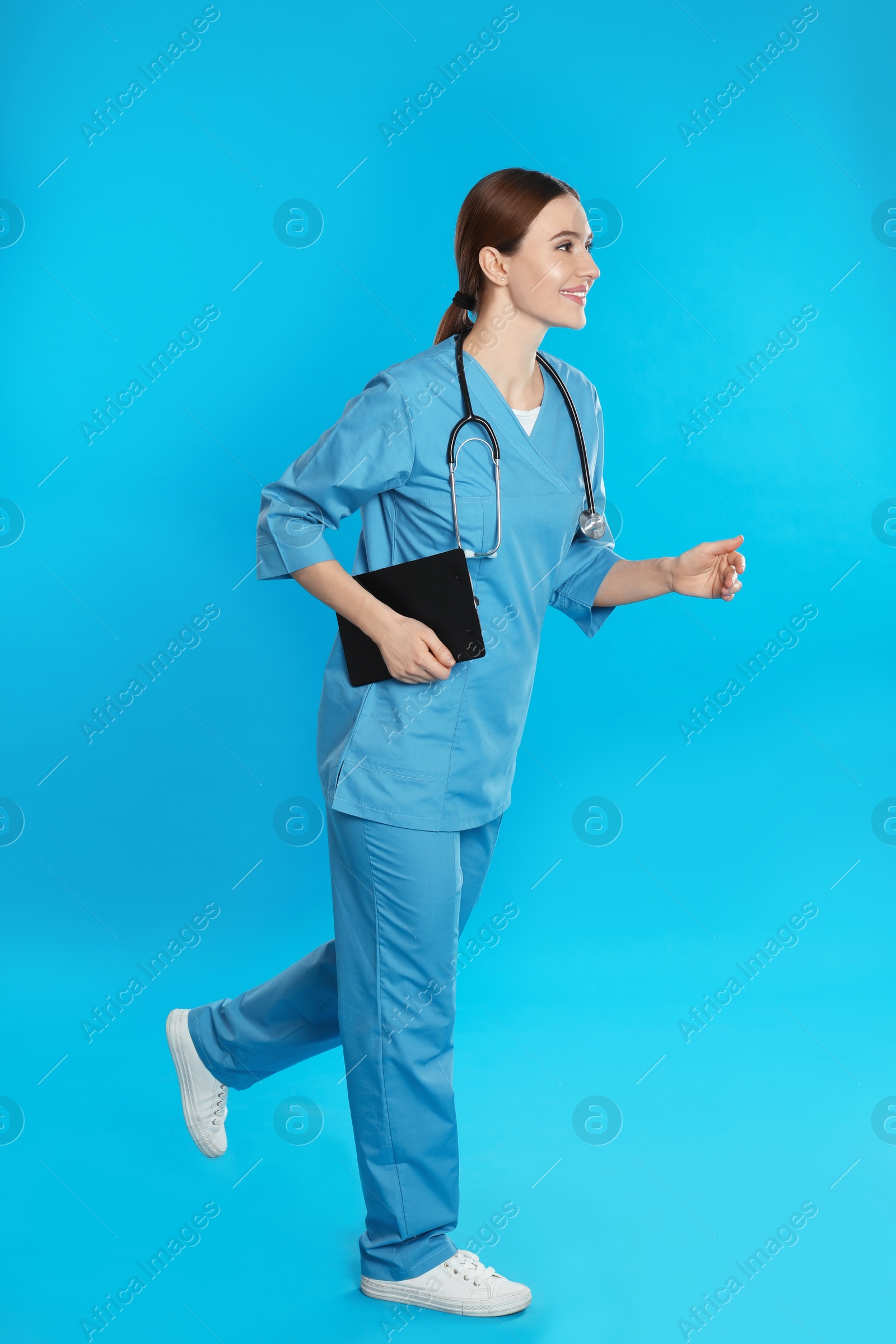 Photo of Doctor with clipboard and stethoscope running on blue background