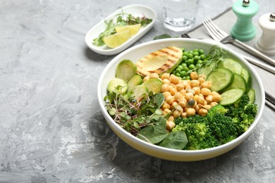 Photo of Healthy meal. Tasty vegetables and chickpeas in bowl on grey table, space for text