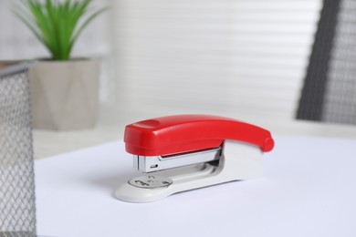 Photo of Bright stapler and paper on table indoors, closeup