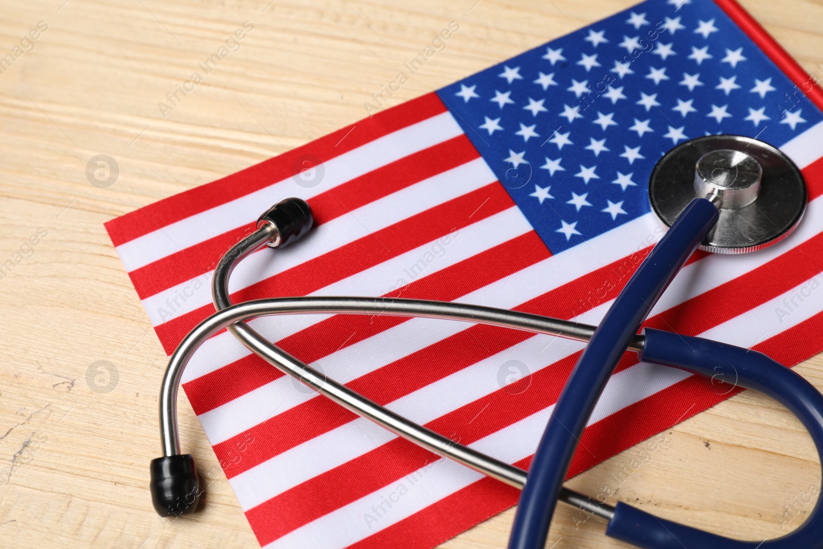 Photo of Stethoscope and USA flag on wooden table, closeup. Health care concept