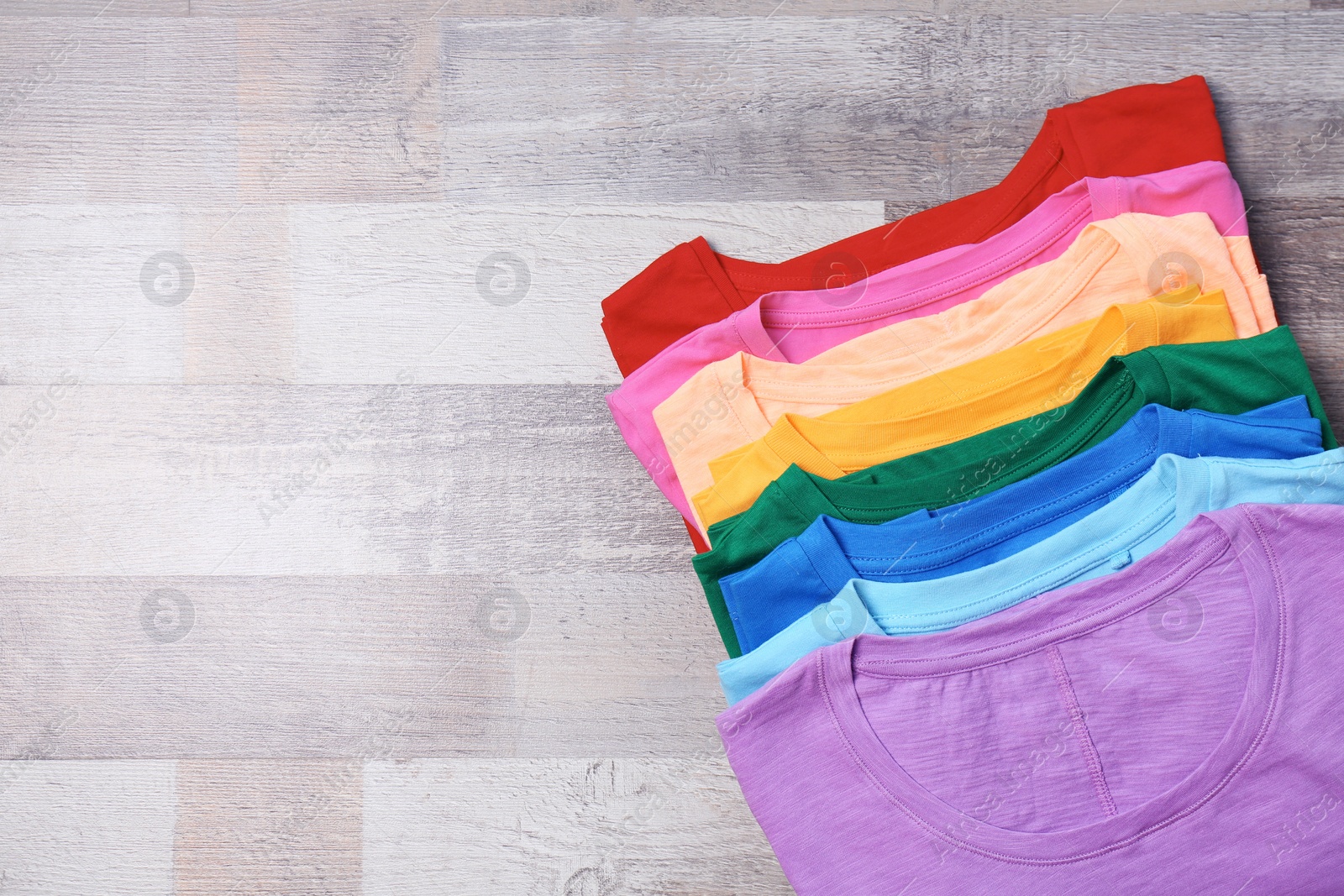 Photo of Colorful collection of t-shirts on wooden background