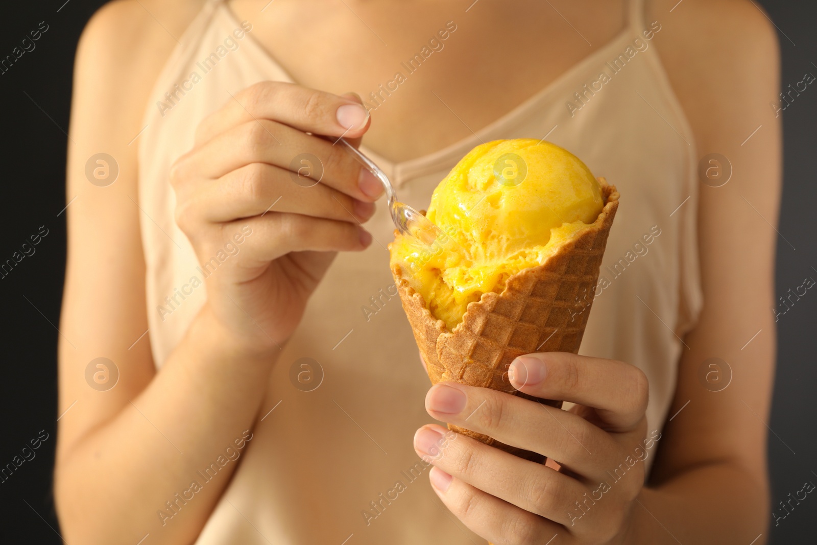 Photo of Woman eating yellow ice cream in wafer cone, closeup