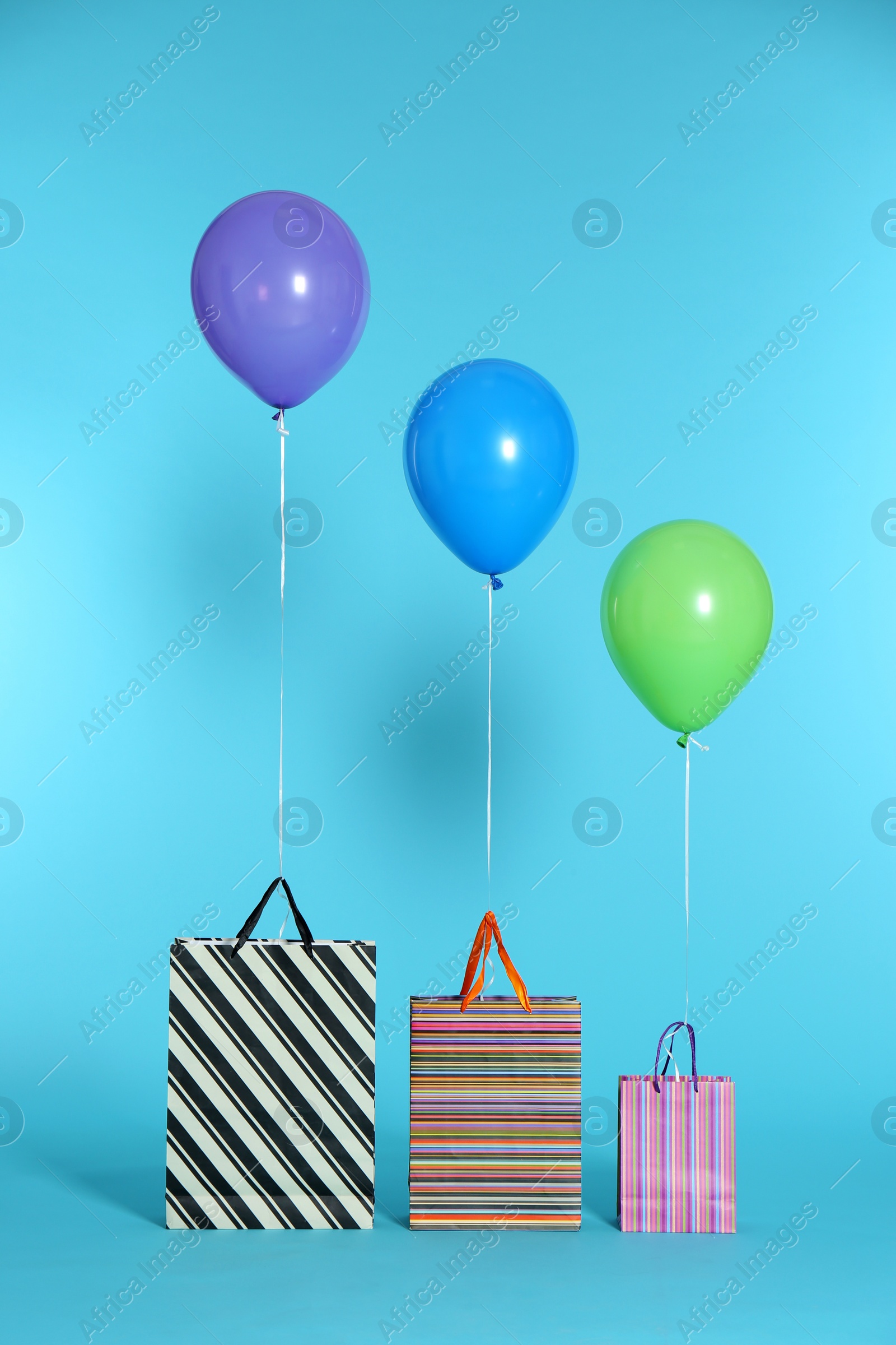 Photo of Paper bags with bright air balloons on color background