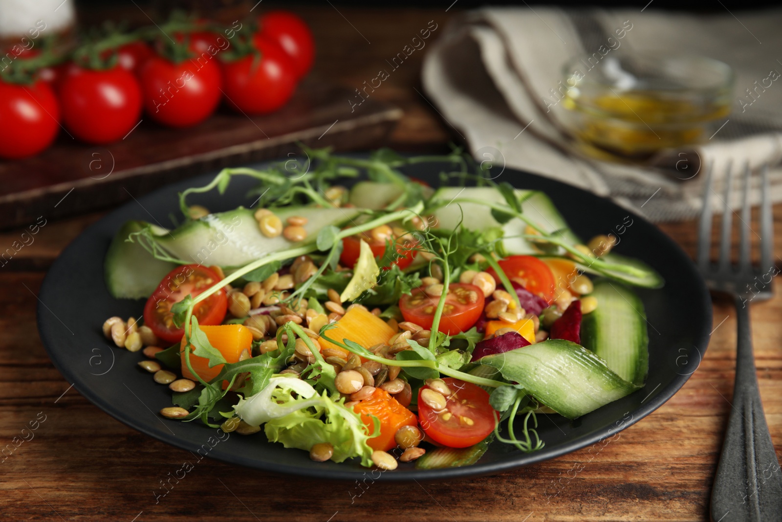 Photo of Delicious salad with lentils and vegetables on wooden table, closeup