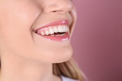 Photo of Young woman with healthy teeth and beautiful smile on color background, closeup. Space for text