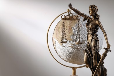 Photo of Symbol of fair treatment under law. Figure of Lady Justice and globe on white background, closeup with space for text