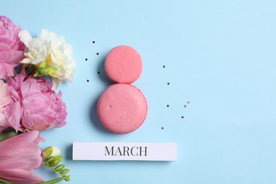 Photo of International Women's day. 8th of March made with delicious macarons and beautiful flowers on light blue background, flat lay. Space for text