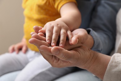 Photo of Family holding hands together on beige background, closeup
