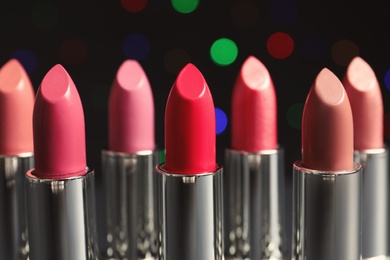 Photo of Different lipsticks against blurred lights. Cosmetic product