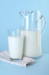 Photo of Jug and glass of fresh milk on light blue background