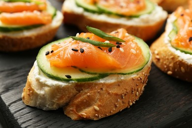 Photo of Tasty canapes with salmon, cucumber and cream cheese on table, closeup