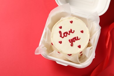 Photo of Bento cake with Love You text in takeaway box on red table, top view. Space for text. St. Valentine's day surprise