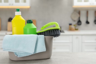 Photo of Different cleaning supplies in basket on table. Space for text