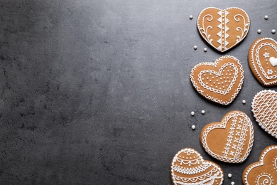 Photo of Tasty heart shaped gingerbread cookies on black table, flat lay. Space for text