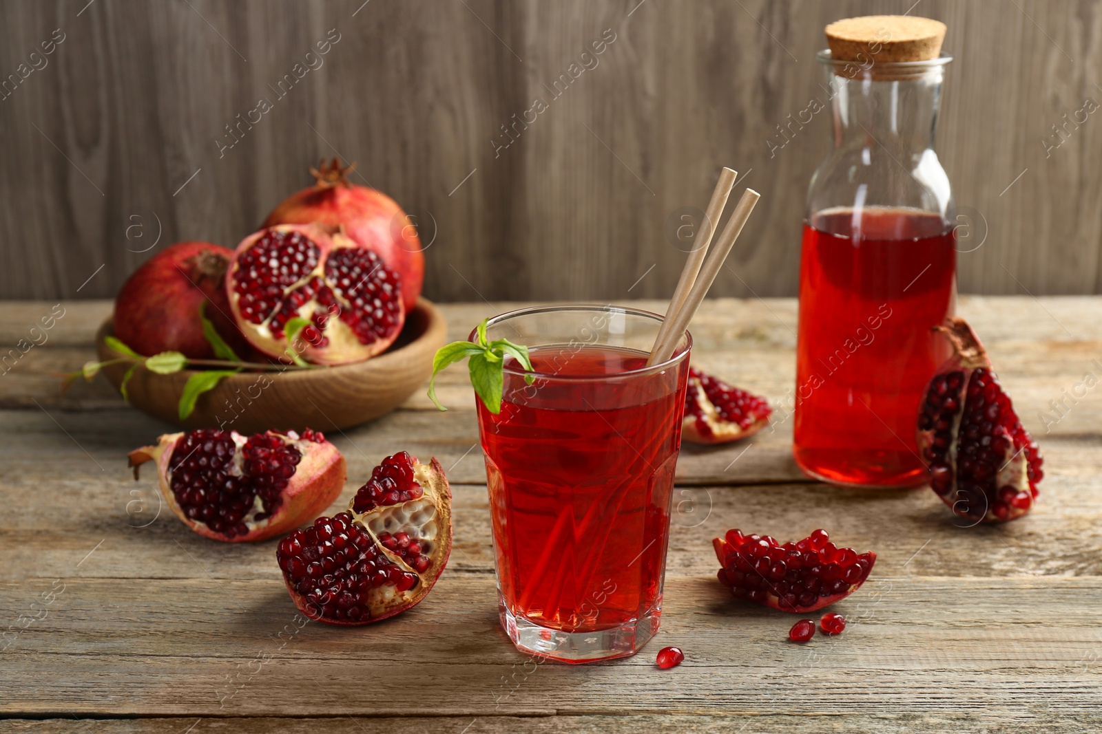 Photo of Tasty pomegranate juice in glass and fresh fruits on wooden table