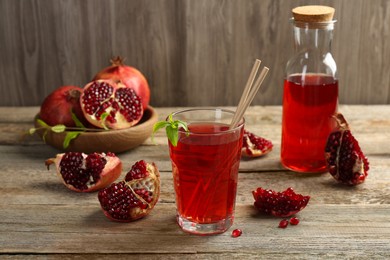 Photo of Tasty pomegranate juice in glass and fresh fruits on wooden table