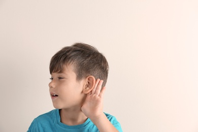 Cute little boy with hearing problem on light background. Space for text