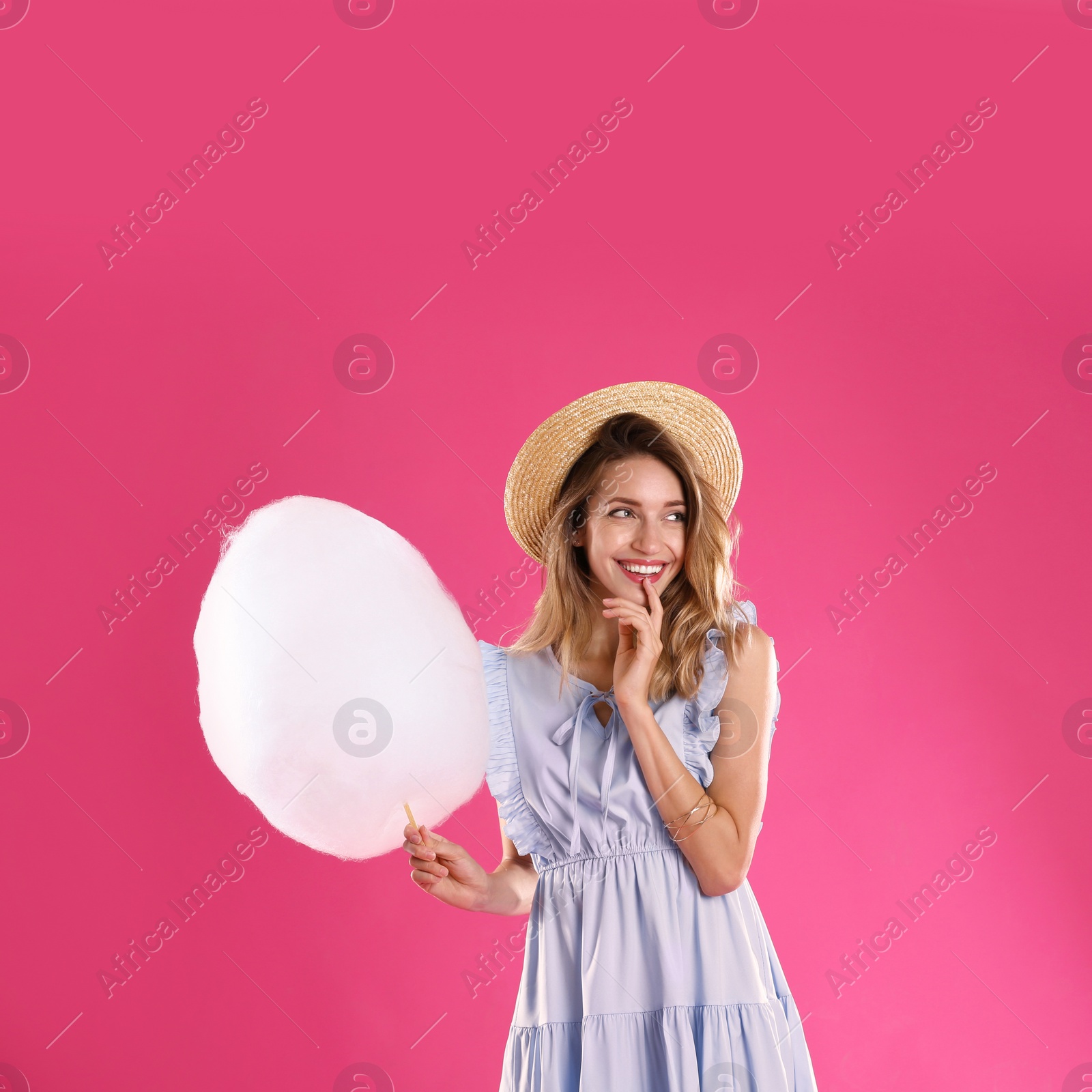 Photo of Happy young woman with cotton candy on pink background