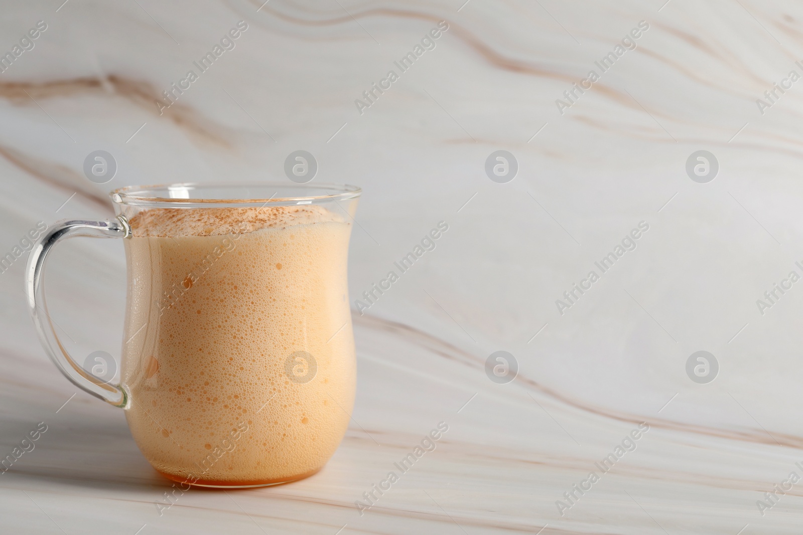 Photo of Delicious eggnog on white marble table. Space for text