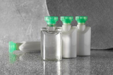 Mini bottles of cosmetic products on grey textured table