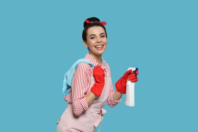 Photo of Young housewife with detergent and rug on light blue background
