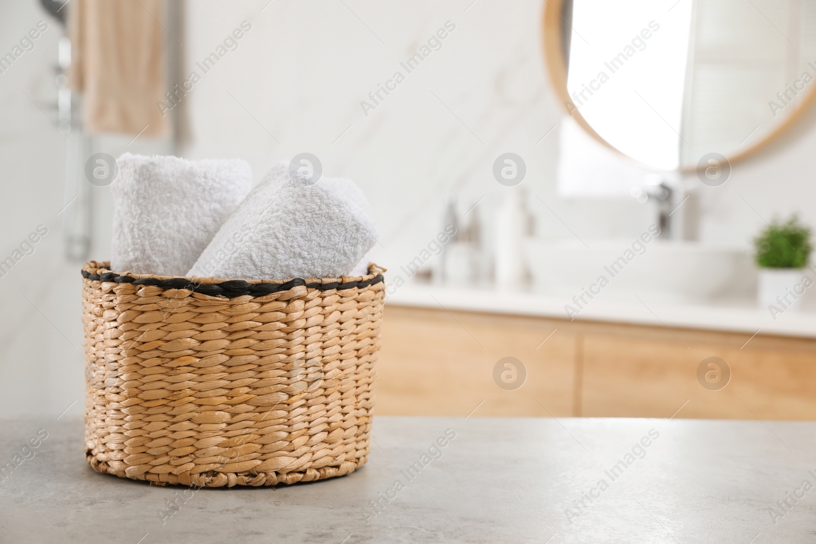 Photo of Rolled fresh towels on grey table in bathroom. Space for text