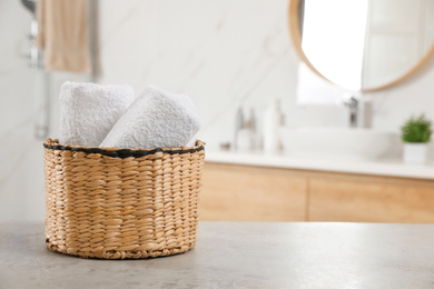 Rolled fresh towels on grey table in bathroom. Space for text