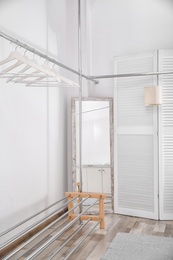 Photo of Empty modern dressing room with racks and hangers