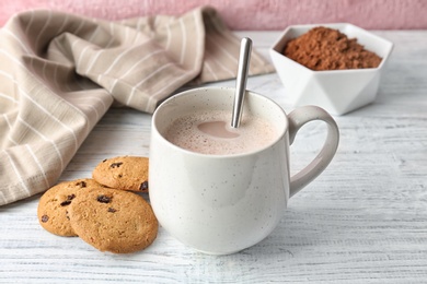 Photo of Tasty cookies and mug with hot cocoa drink on table
