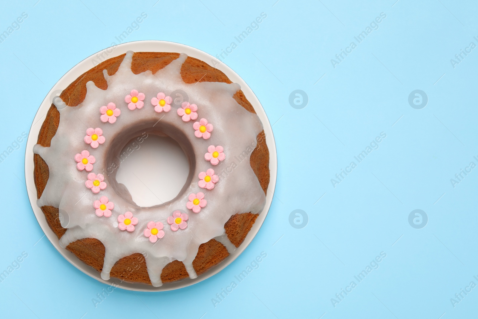 Photo of Delicious Easter cake decorated with sprinkles on light blue background, top view. Space for text