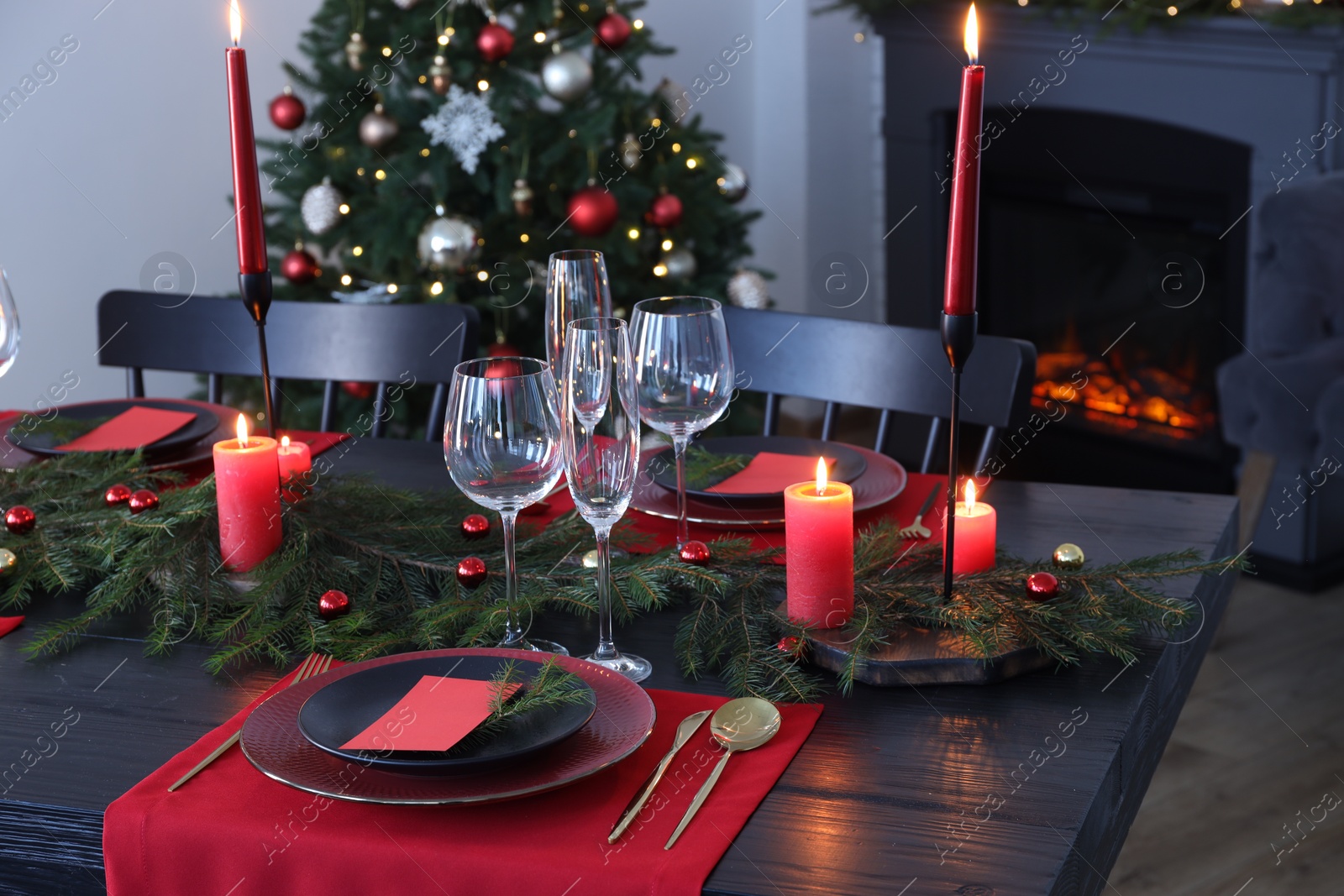 Photo of Elegant Christmas table setting with dishware and burning candles in festively decorated room