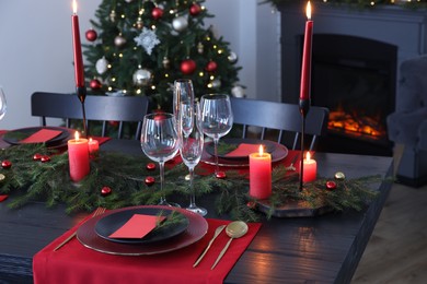 Elegant Christmas table setting with dishware and burning candles in festively decorated room
